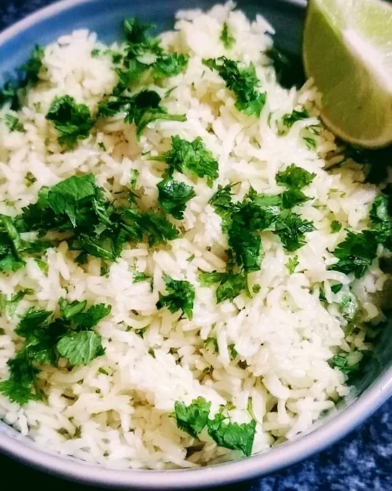 Bowl of cilantro lime rice garnished with fresh cilantro and lime wedges