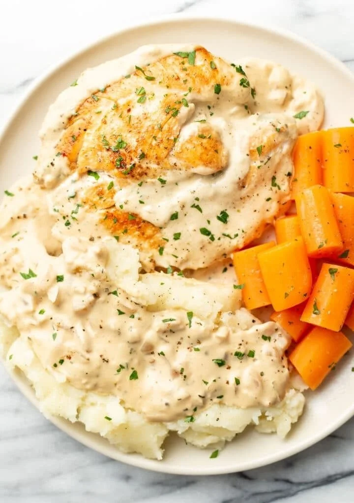 A plate of easy cream cheese chicken garnished with herbs and served with rice.
