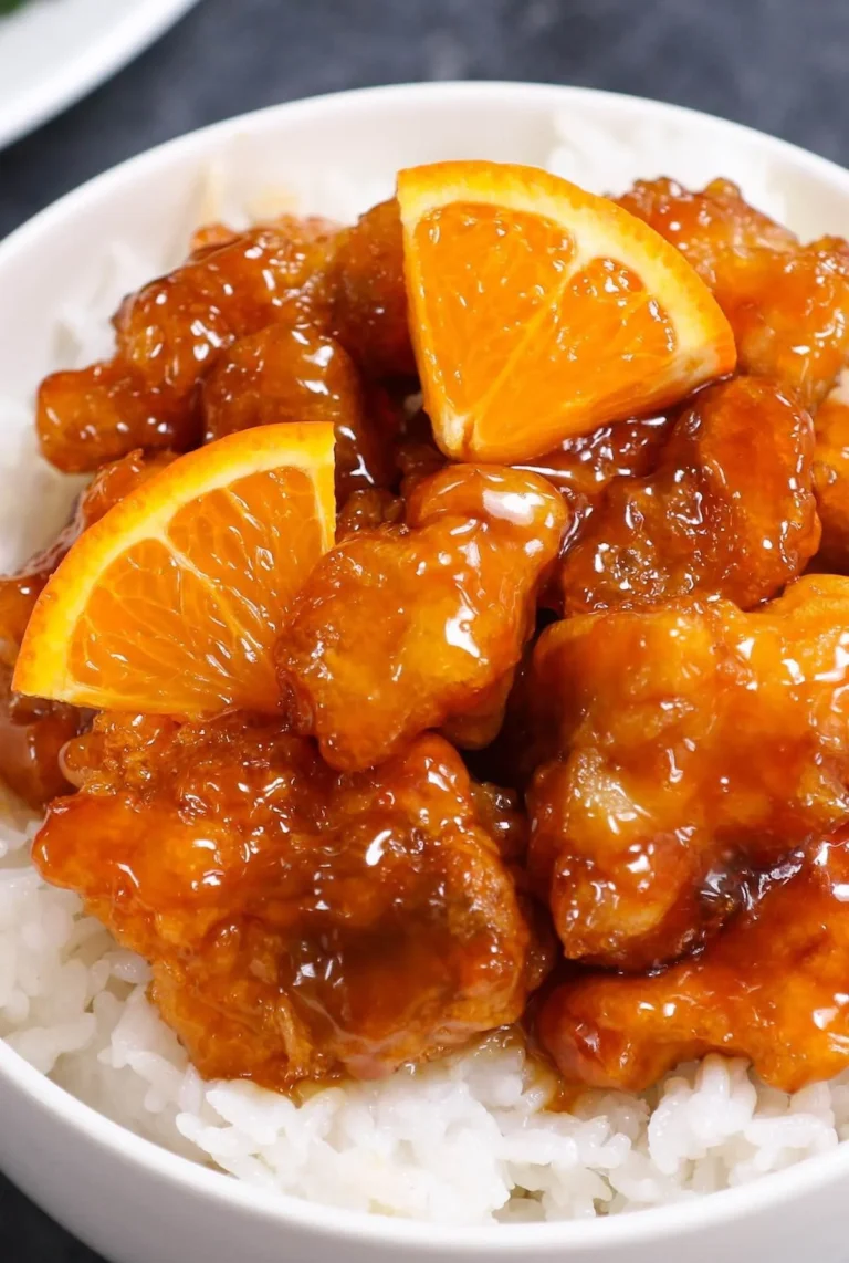 Plate of tasty orange chicken garnished with sesame seeds and green onions