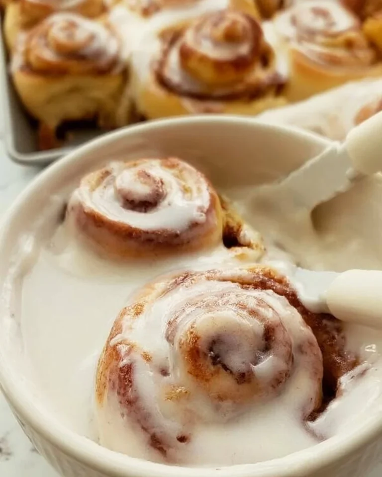 Delicious homemade cinnamon roll icing drizzled over warm cinnamon rolls